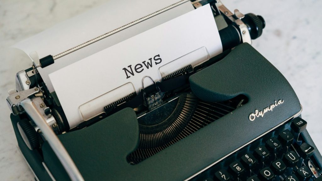 A vintage typewriter with a sheet of paper reading "News".